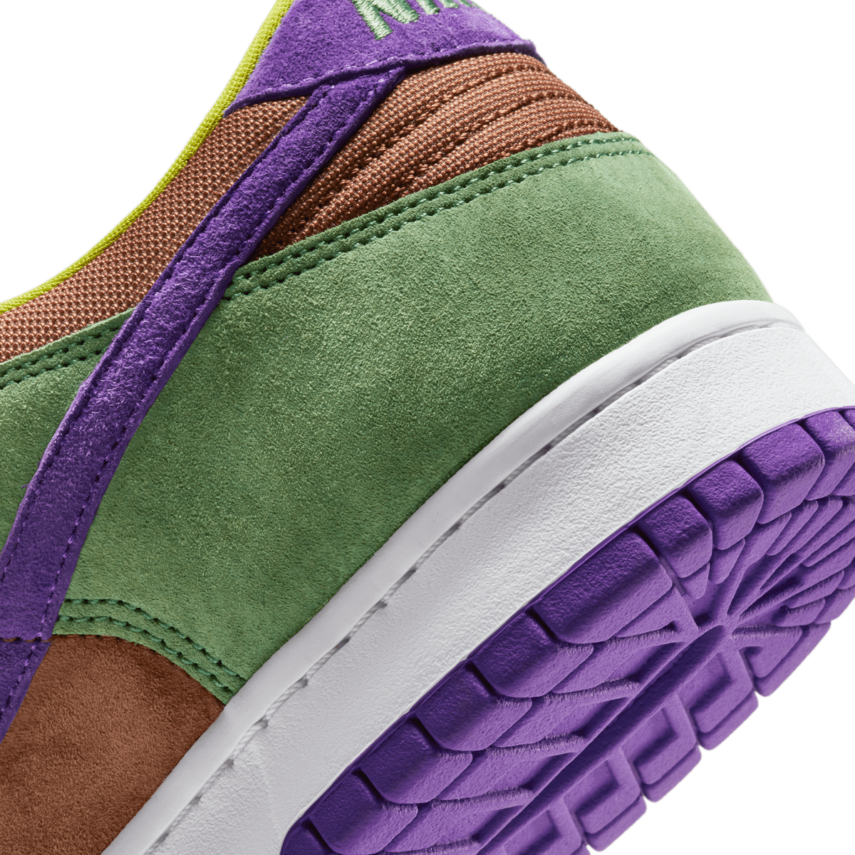 Close-up of a Nike Dunk Low's heel and midsole showing green suede, brown textured fabric, purple laces and outsole, and a white midsole panel.