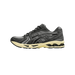 Left Asics Gel-Kayano 14 sneaker in dark grey mesh and suede with black stripe overlays and a cream midsole, shown from the outside with toe pointing left