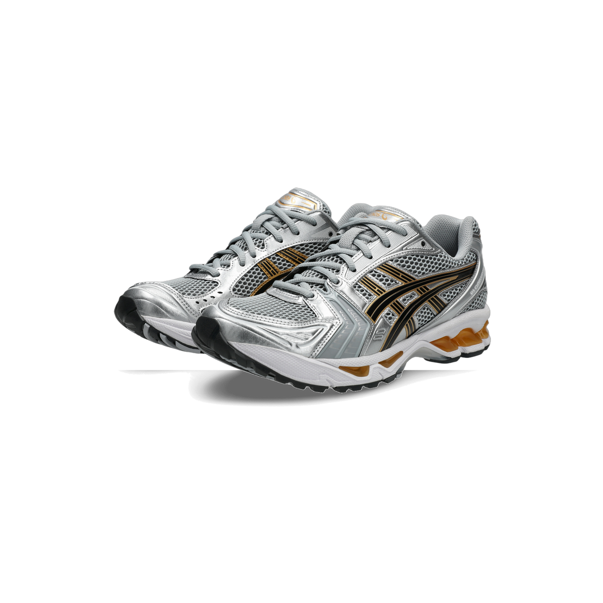 Pair of Asics Gel-Kayano 14 running shoes in silver mesh with black and gold stripes and an orange gel heel unit, angled toward the left
