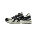 Side view of a white and black Asics Gel-Kayano 20 sneaker with toe pointing left, featuring mesh upper, black overlays, strap detailing, and a cream midsole.