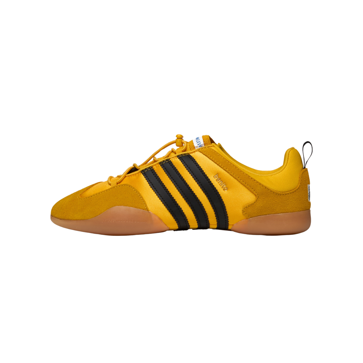 Side view of a gold adidas Ballerina Bad Bunny sneaker with black stripes, suede toe and heel panels, gum sole, and a pull tab at the heel, toe pointing left.