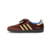 Left view of a brown Adidas Samba sneaker with tan three stripes, suede toe and heel panels, blue interior lining, and Wales Bonner text near the heel