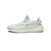 Side view of a single Adidas Yeezy Boost 350 V2 sneaker in light gray knit with a tan side stripe and translucent midsole, toe pointing left.