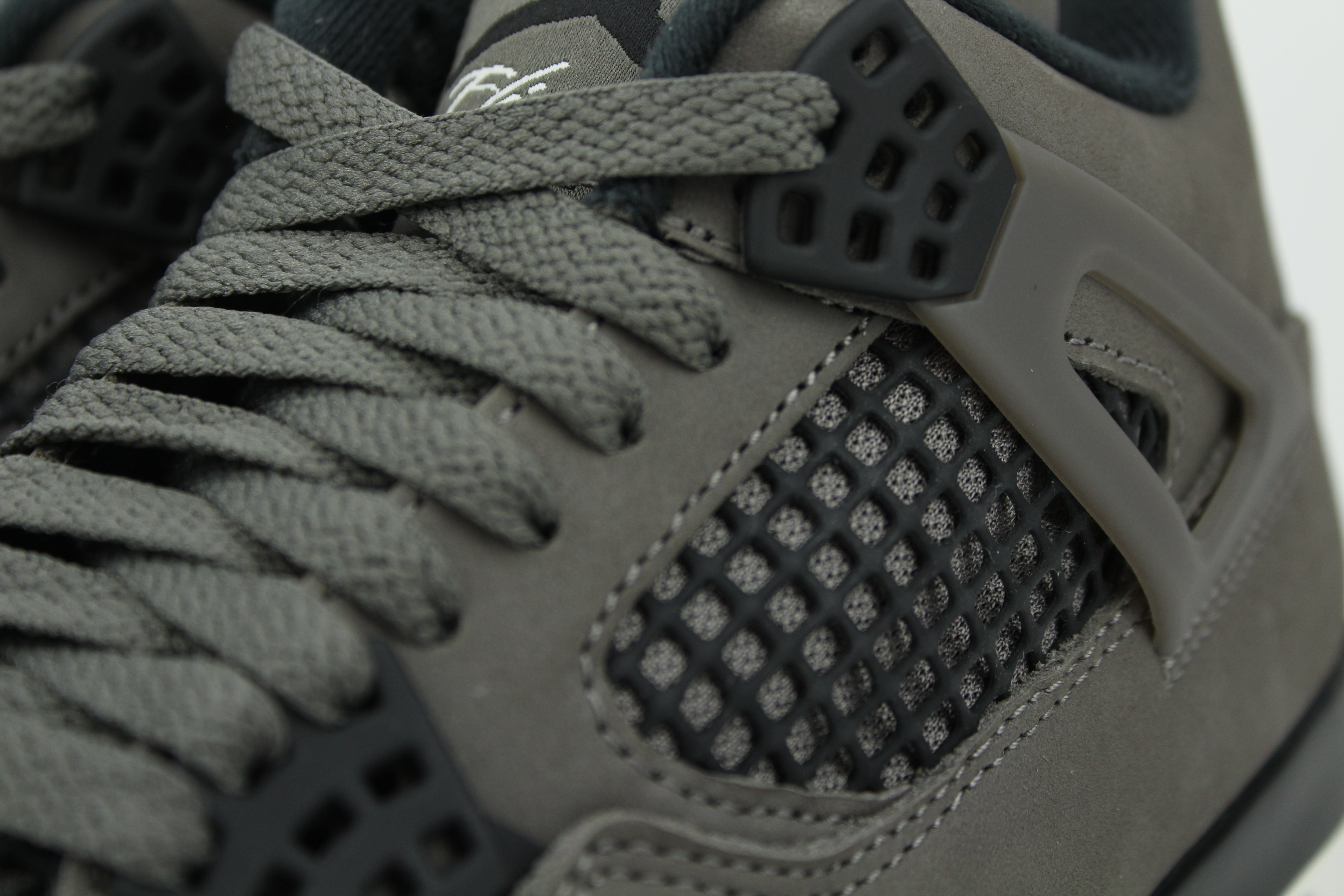 The Air Jordan 4 Cave Stone reimagines the classic silhouette with an earthy nubuck upper in taupe-brown tones, contrasted by bold black mesh and details. Travis Scott vibes.