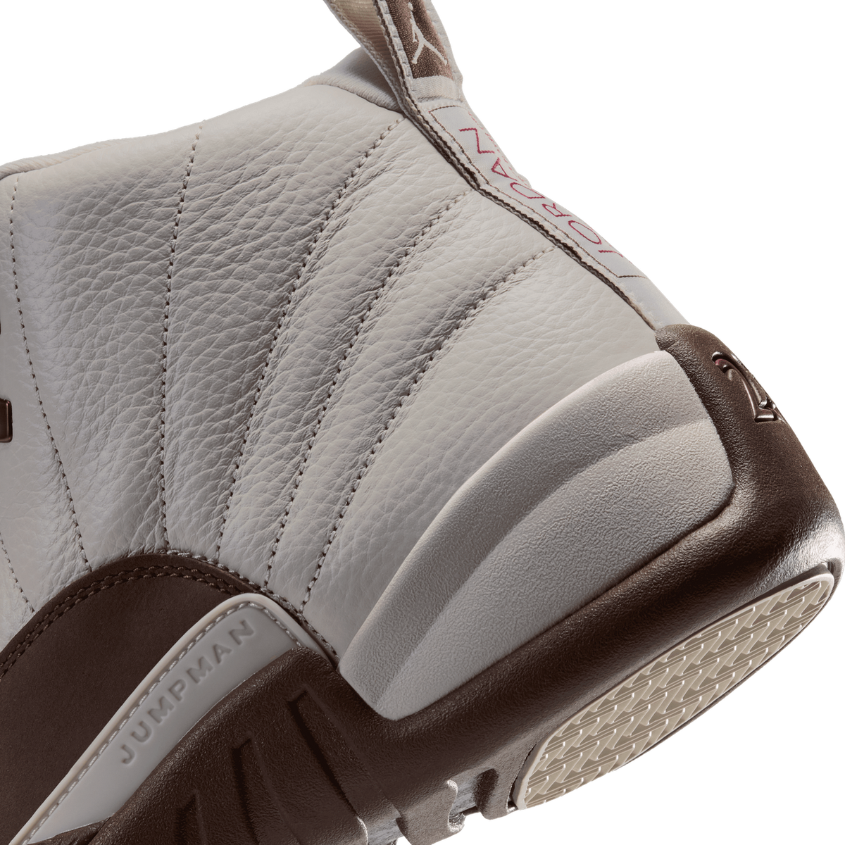 Close-up angled view of a white leather Air Jordan 12 showing the ribbed vamp panels, Jumpman insole text, brown heel and outsole tread.