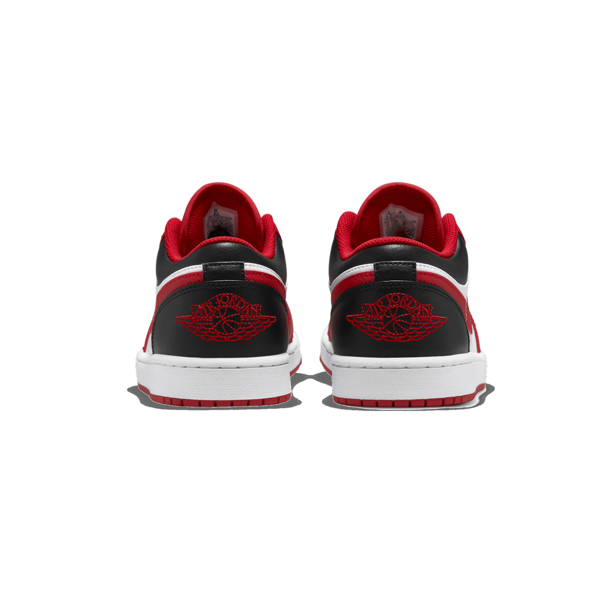 A pair of Air Jordan 1 Low sneakers in white, red, and black photographed from the rear, showing the red Air Jordan wings logo embroidered on each black heel and the white midsole and red outsole edge.
