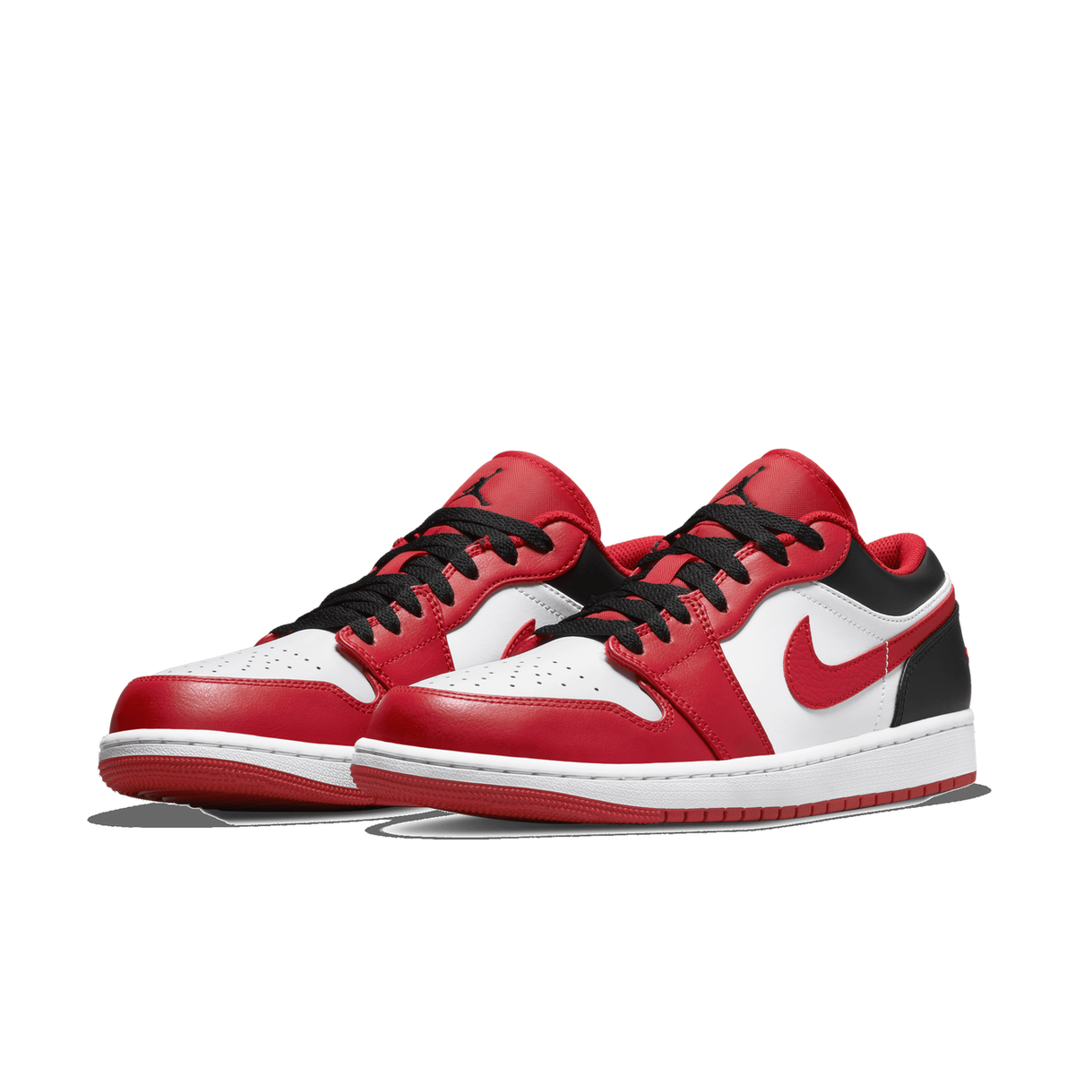 A pair of red, white, and black Air Jordan 1 Low sneakers shown side by side at a three-quarter angle, with the left shoe's toe pointing toward the viewer and the right shoe angled behind it.