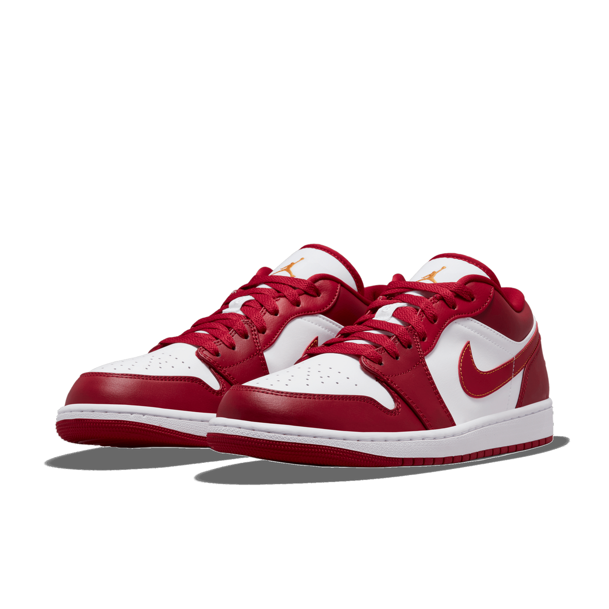 A pair of red and white Air Jordan 1 Low sneakers angled side by side against a white background, showing the red leather overlays, white toe boxes with perforations, red laces, and orange Jumpman logos on the tongues.