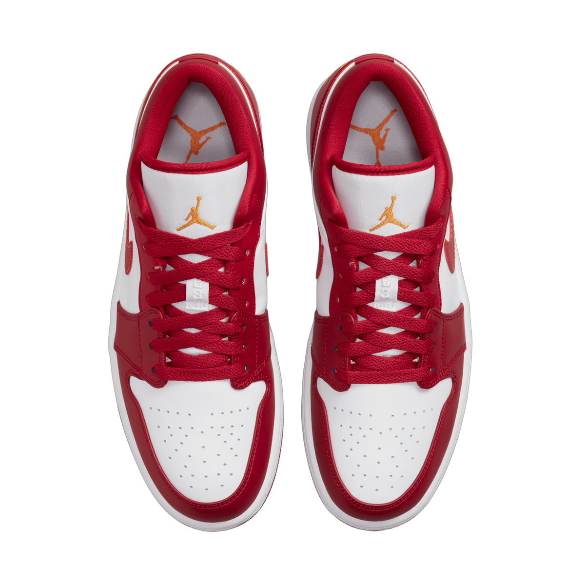 Overhead top-down view of a pair of red and white Air Jordan 1 Low sneakers placed side by side, showing the laces, tongues with orange Jumpman logos, and the perforated white toe boxes.