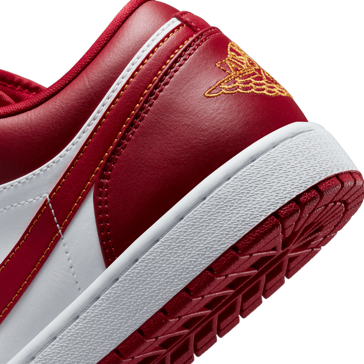 Close-up of the heel and rear quarter of a red and white Air Jordan 1 Low, showing gold Jumpman wing embroidery on the heel, red and white leather panels, and the white and red rubber sole with textured tread.