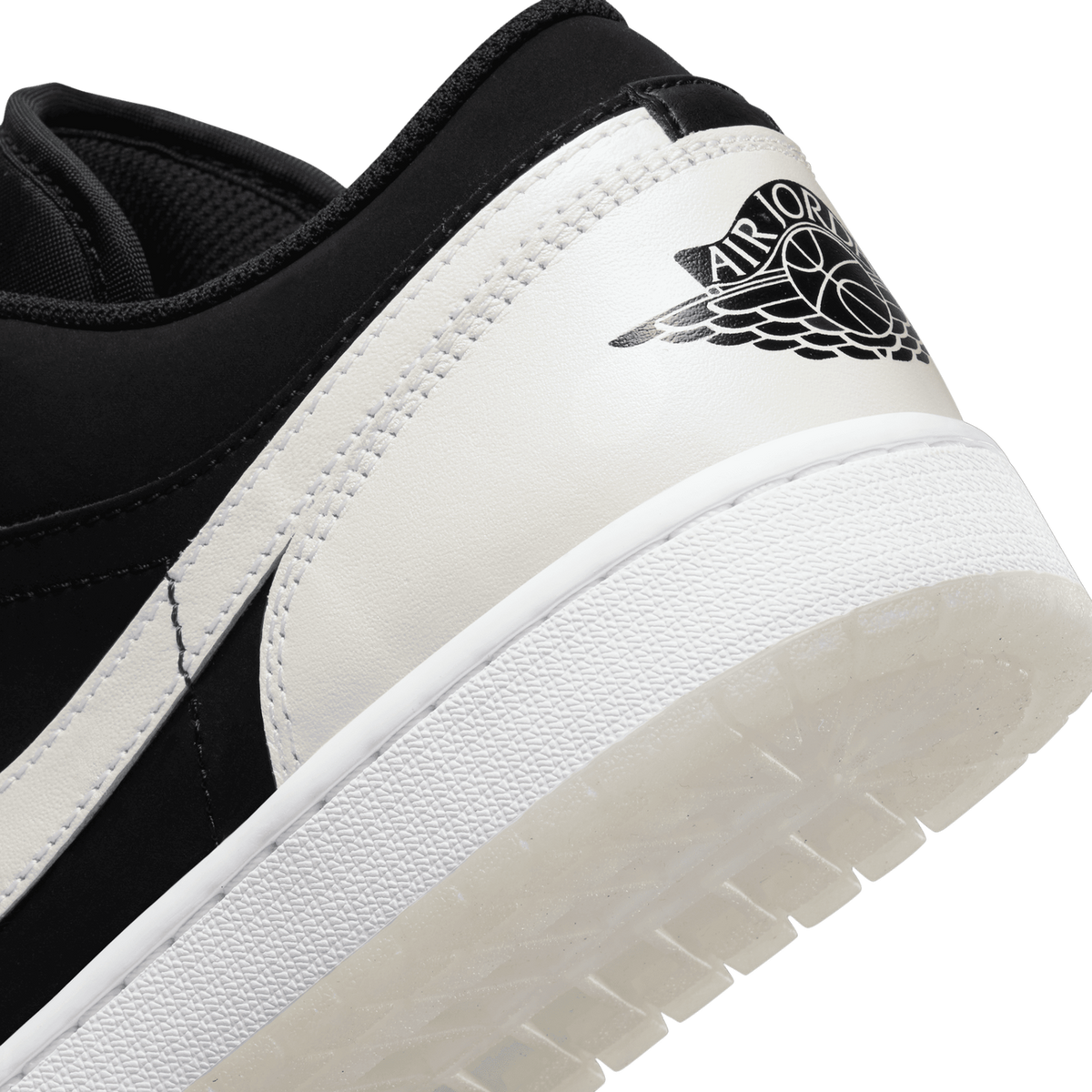 Close-up of the black and white Air Jordan 1 Low heel showing the Wings logo printed on the white heel panel above the sole.