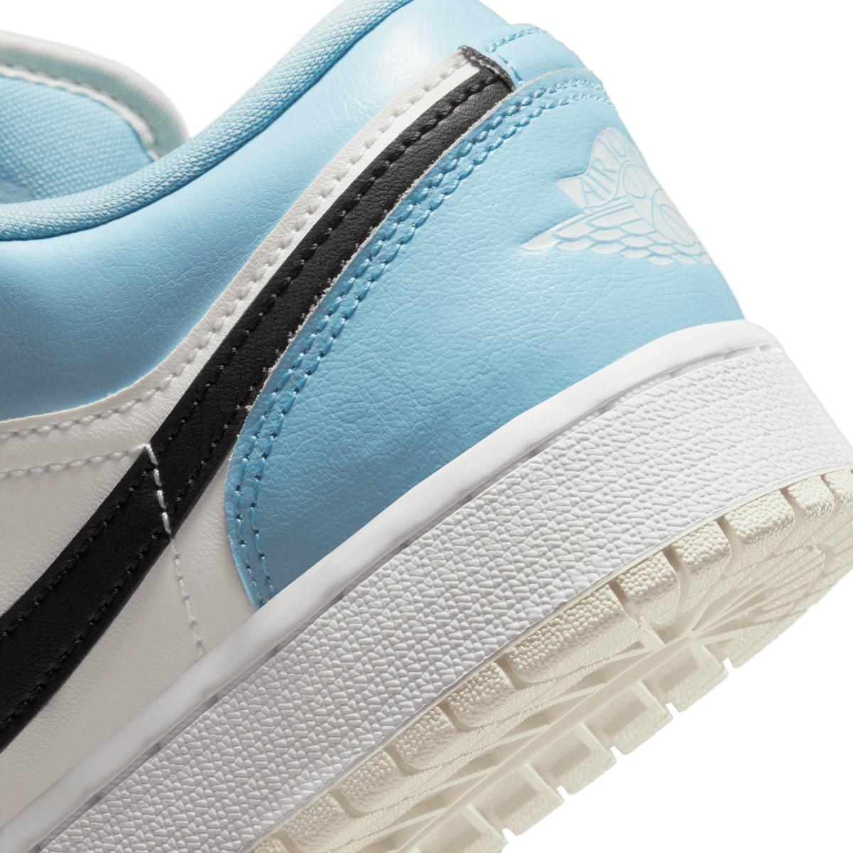 Close-up of the heel and outsole area of a blue, white, and black Jordan 1 Low sneaker showing the Wings logo and textured rubber sole.