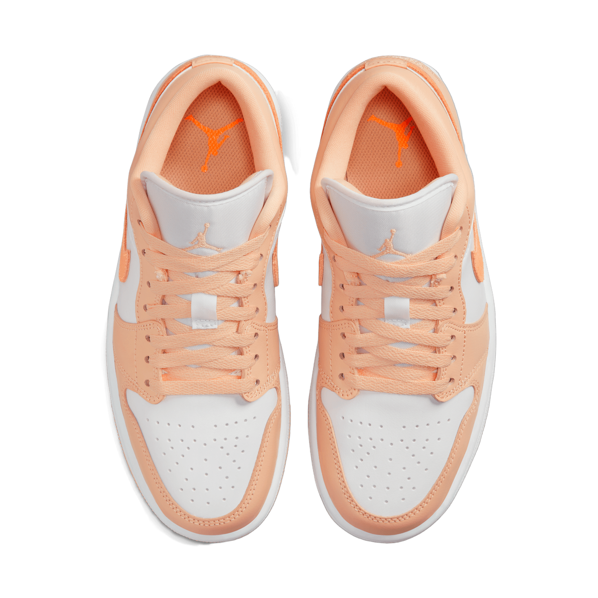 Overhead top-down view of a pair of peach-orange and white low-top sneakers placed side by side, showing the laces, tongues with orange Jumpman logos, and the white toe boxes with perforations.
