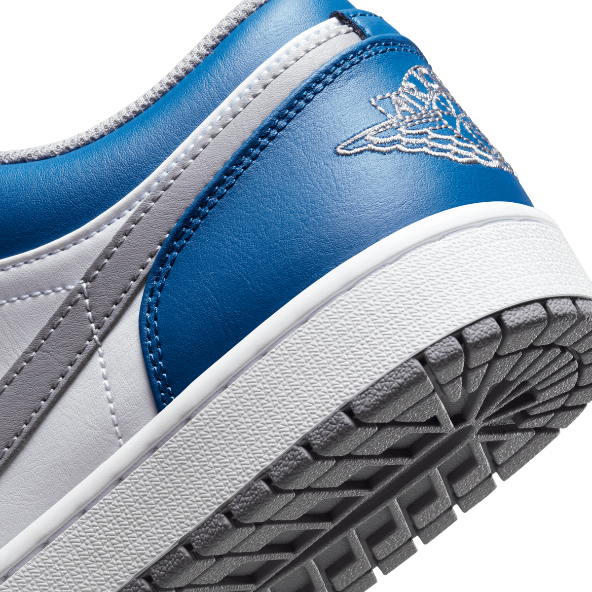 Close-up of a blue, white, and grey Jordan 1 Low heel showing the embroidered Jumpman wings logo and textured outsole tread.