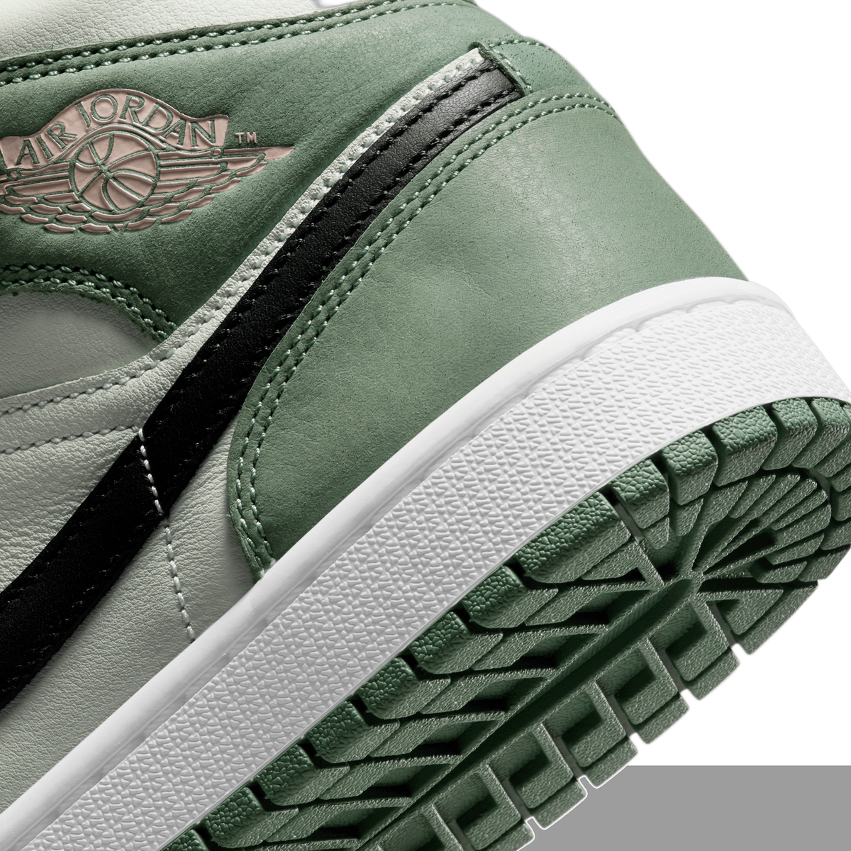 Close-up view of a Jordan 1 Mid sneaker showing the Wings logo, green suede and leather paneling, black vertical stripe, and textured rubber outsole.