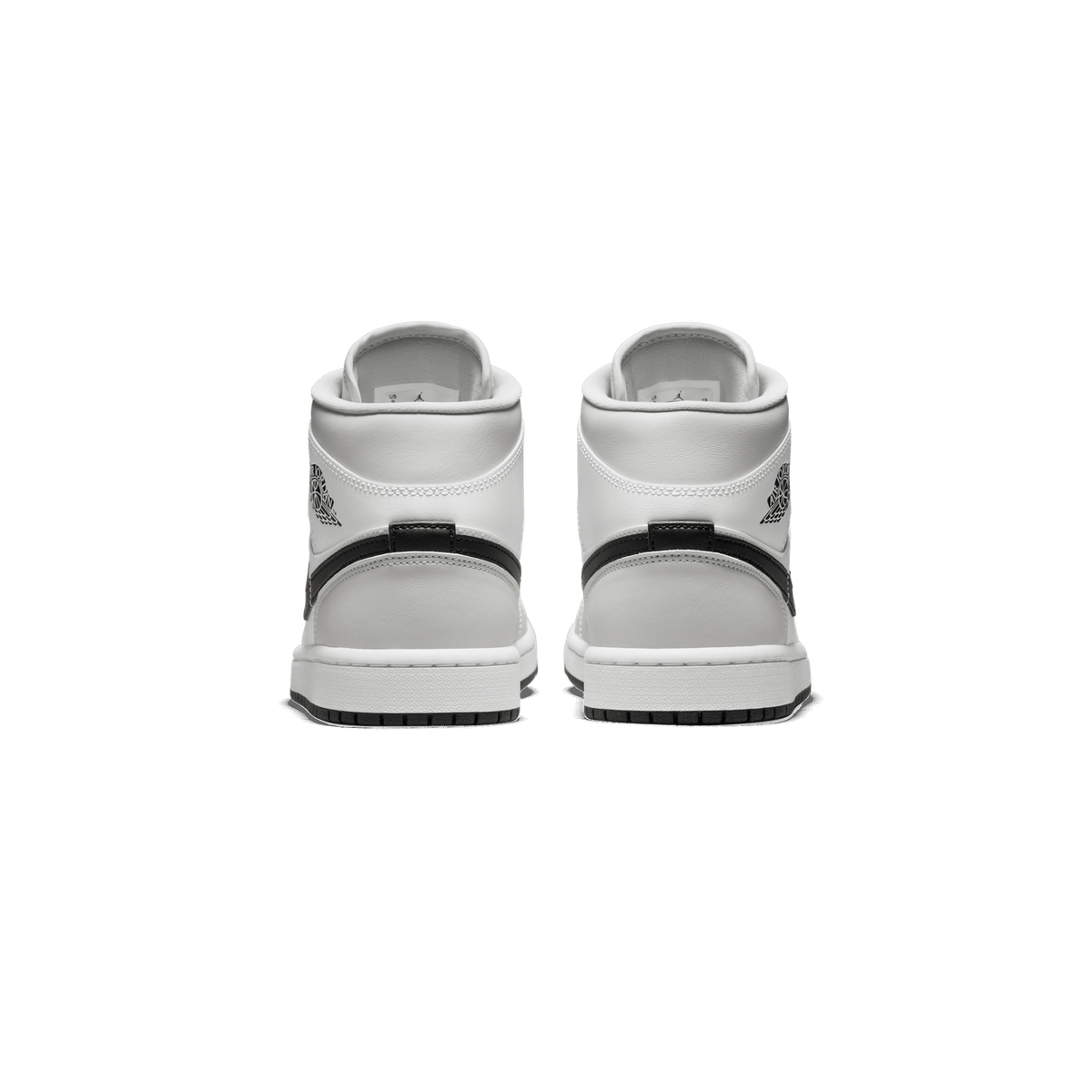 Rear view of a pair of grey and white Air Jordan 1 Mid sneakers showing the heel tabs with Wings logo and black pull straps.