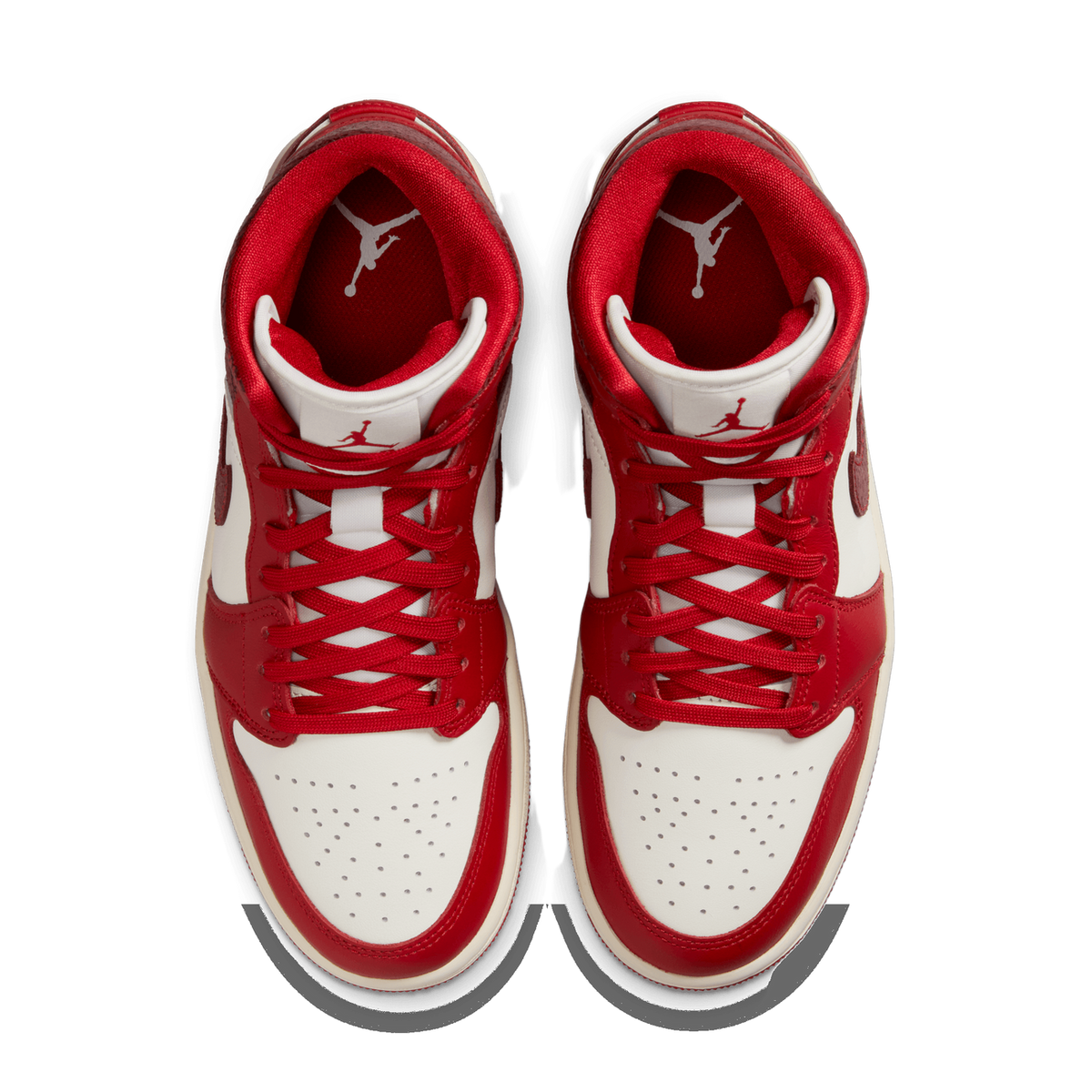 Top-down view of a pair of red and white Jordan 1 Mid sneakers with red laces and Jumpman logo on the tongues.