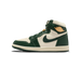 Side profile of a single high-top Air Jordan 1 sneaker with the toe pointing left, showing dark green leather overlays, cream/off-white panels, a green Swoosh, and a gold Air Jordan wings logo on the heel tab.