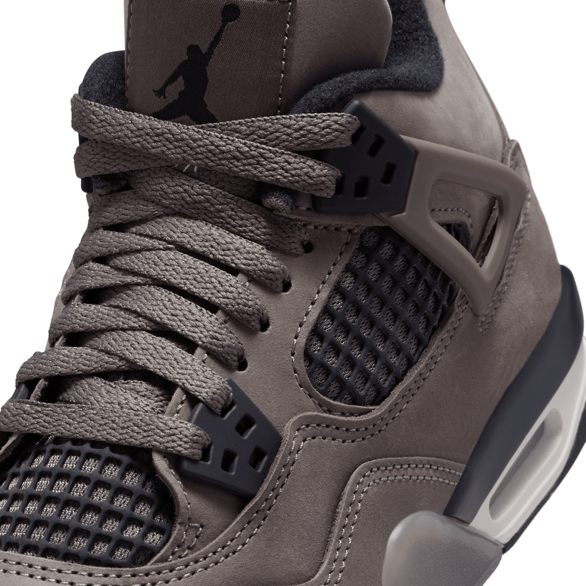 Close-up detail of a grey-brown suede Air Jordan 4 high-top, showing the laces, mesh eyelet panels, black Jordan Jumpman logo on the collar tab, and the visible Air unit in the heel.