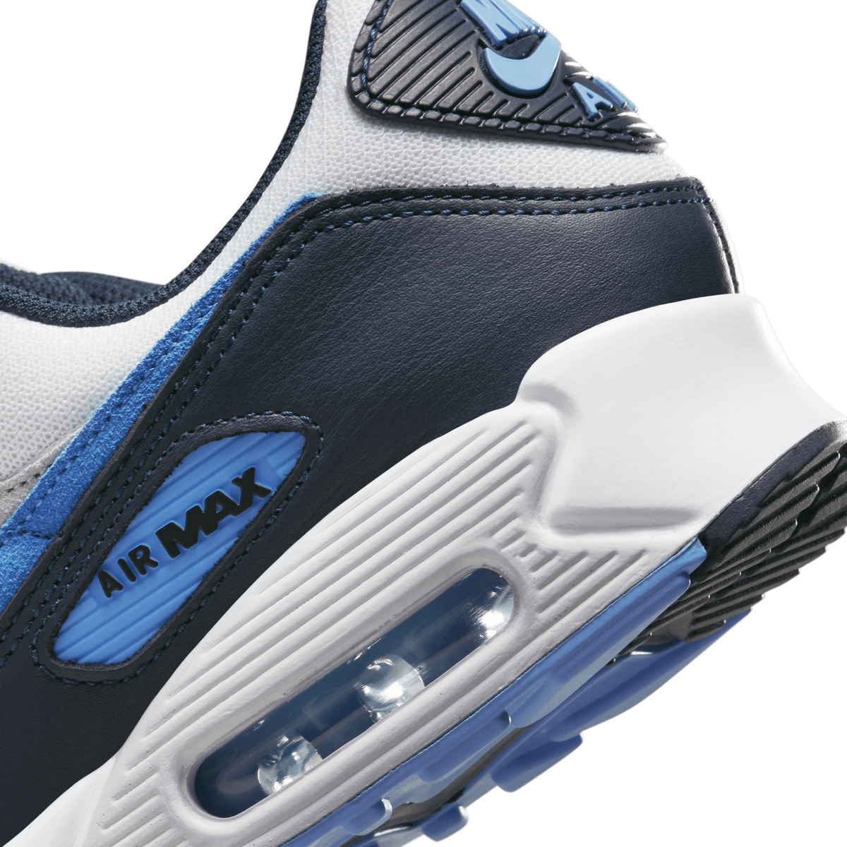 Close-up of a Nike Air Max 90 heel showing the white, navy, and blue colorway with visible Air Max branding and the heel air bubble unit