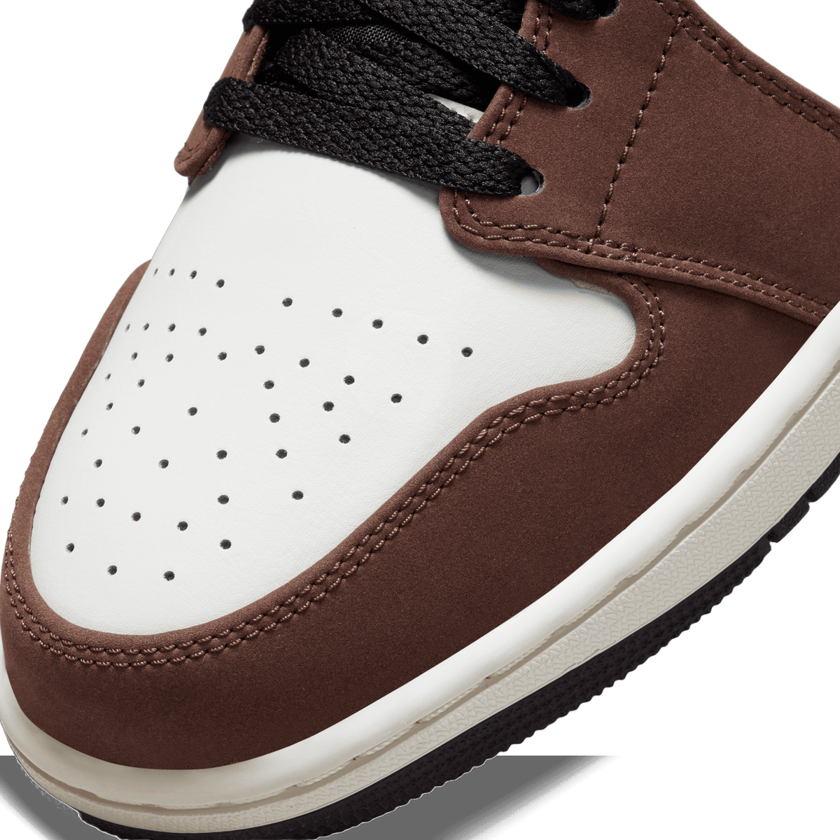 Close-up of the toe box of a brown and white Jordan 1 Low Mocha showing perforated leather, black laces, and stitching detail.