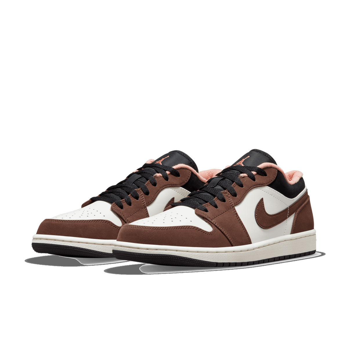 Pair of Air Jordan 1 Low sneakers in brown and white with black laces and peach interior lining, angled toward the left.