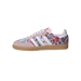 Side view of a pink Adidas Samba sneaker with floral multicolor print, white stripes, pink suede toe and heel, white laces, and a gum sole.
