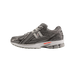 Side view of a gray New Balance 1906R running shoe with black overlays, silver N logo, and a red accent on the midsole, toe pointing left.