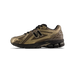 A single New Balance 1906R sneaker in a bronze and brown colourway with black laces and black sole, shown from the outside with the toe pointing right, displaying the large black N logo and 1906R text on the heel panel.