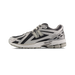 Side view of a grey and black New Balance 1906R sneaker with silver N logo, white midsole, and gray outsole, toe pointing left.
