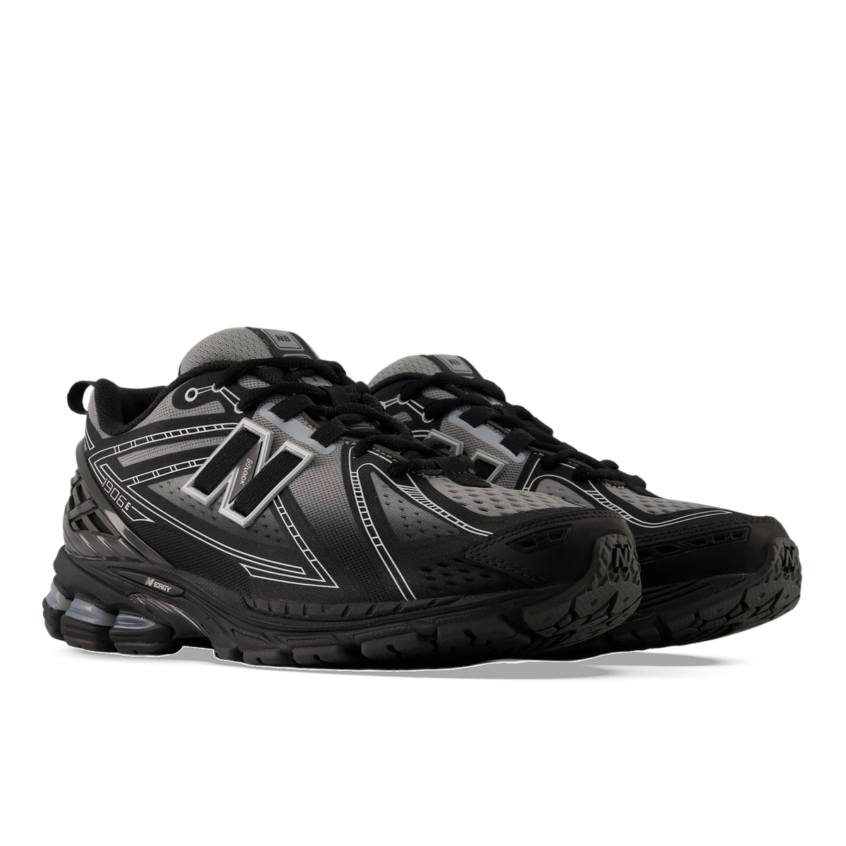 Pair of black and grey New Balance 1906 sneakers with white outline detailing and visible N-Ergy cushioning in the sole, shown from a front side angle