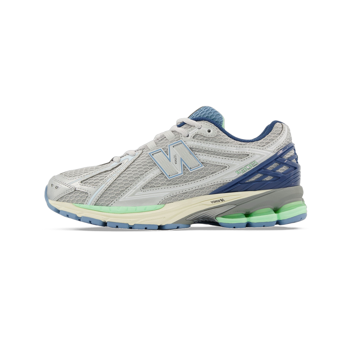 Side view of a gray New Balance 1906R sneaker with navy blue heel accent, light blue N logo, green midsole detailing, and cream outsole.