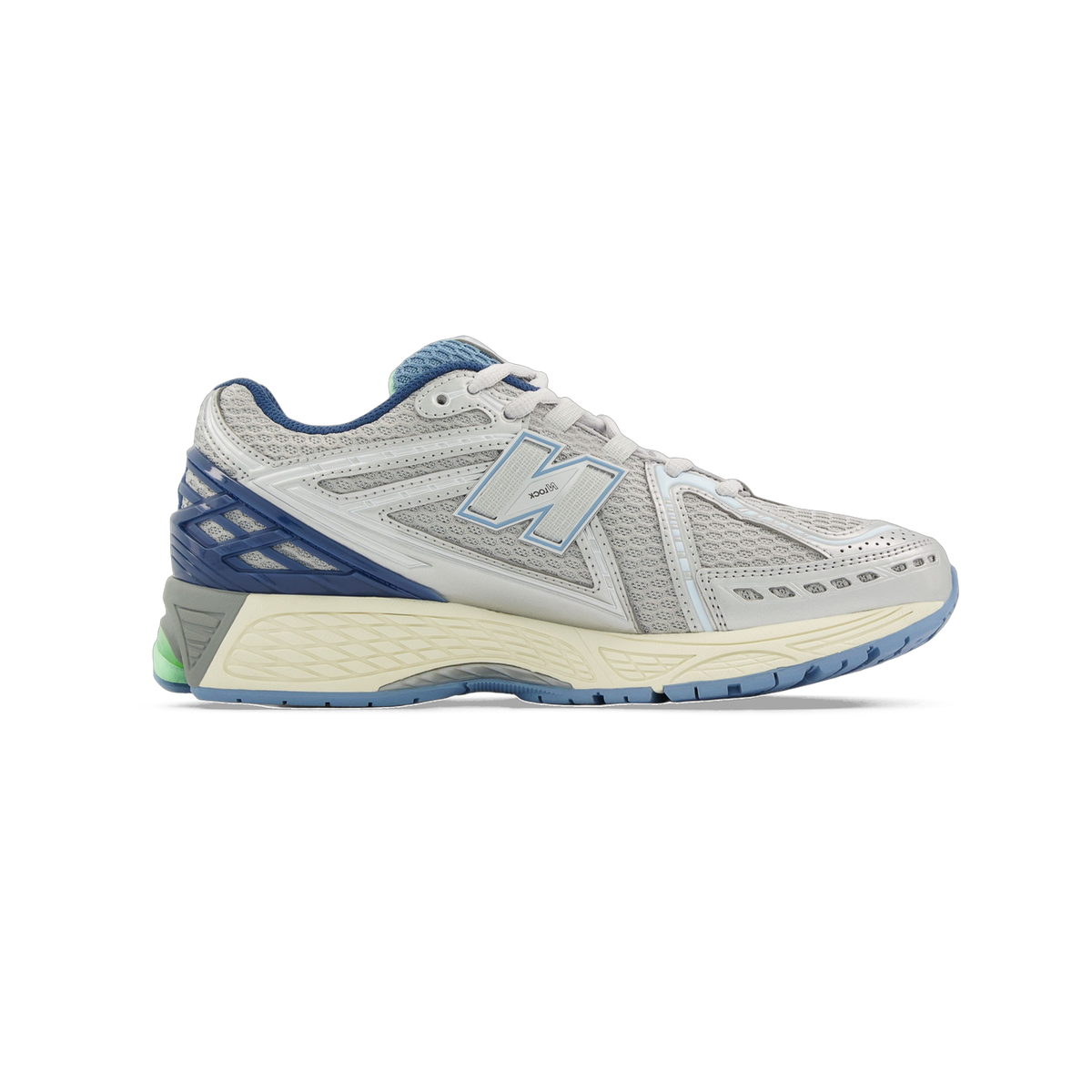 Side view of a gray New Balance 1906 running shoe with a light blue N logo, navy blue heel, cream midsole, and a green accent visible near the heel.