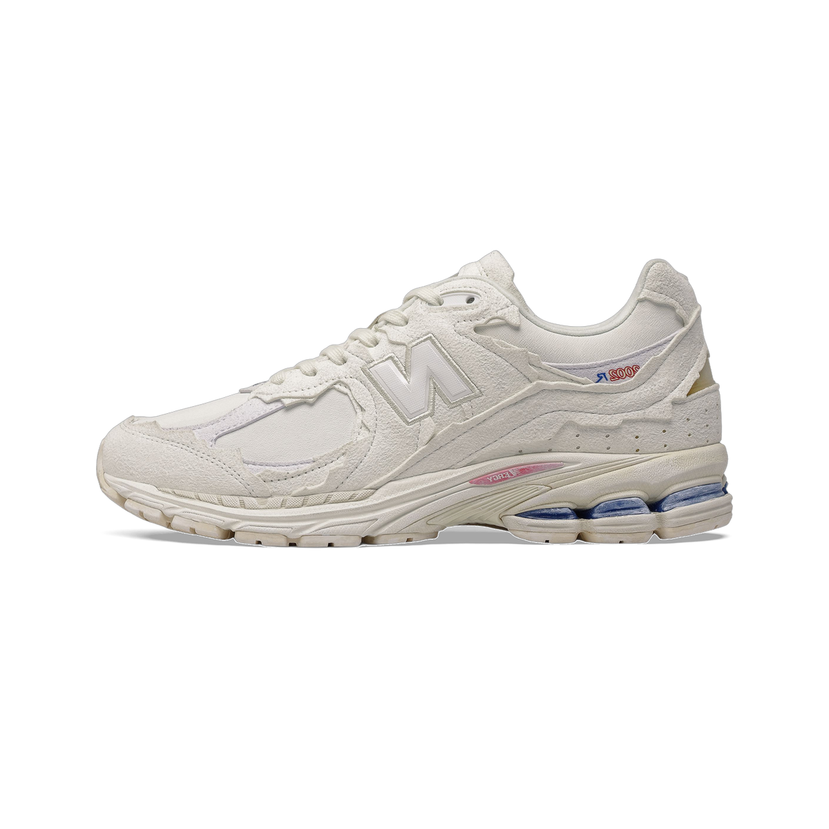 Side view of a white New Balance 2002R sneaker with a raw, deconstructed suede overlay design, layered panels, and a midsole with pink and blue accents.