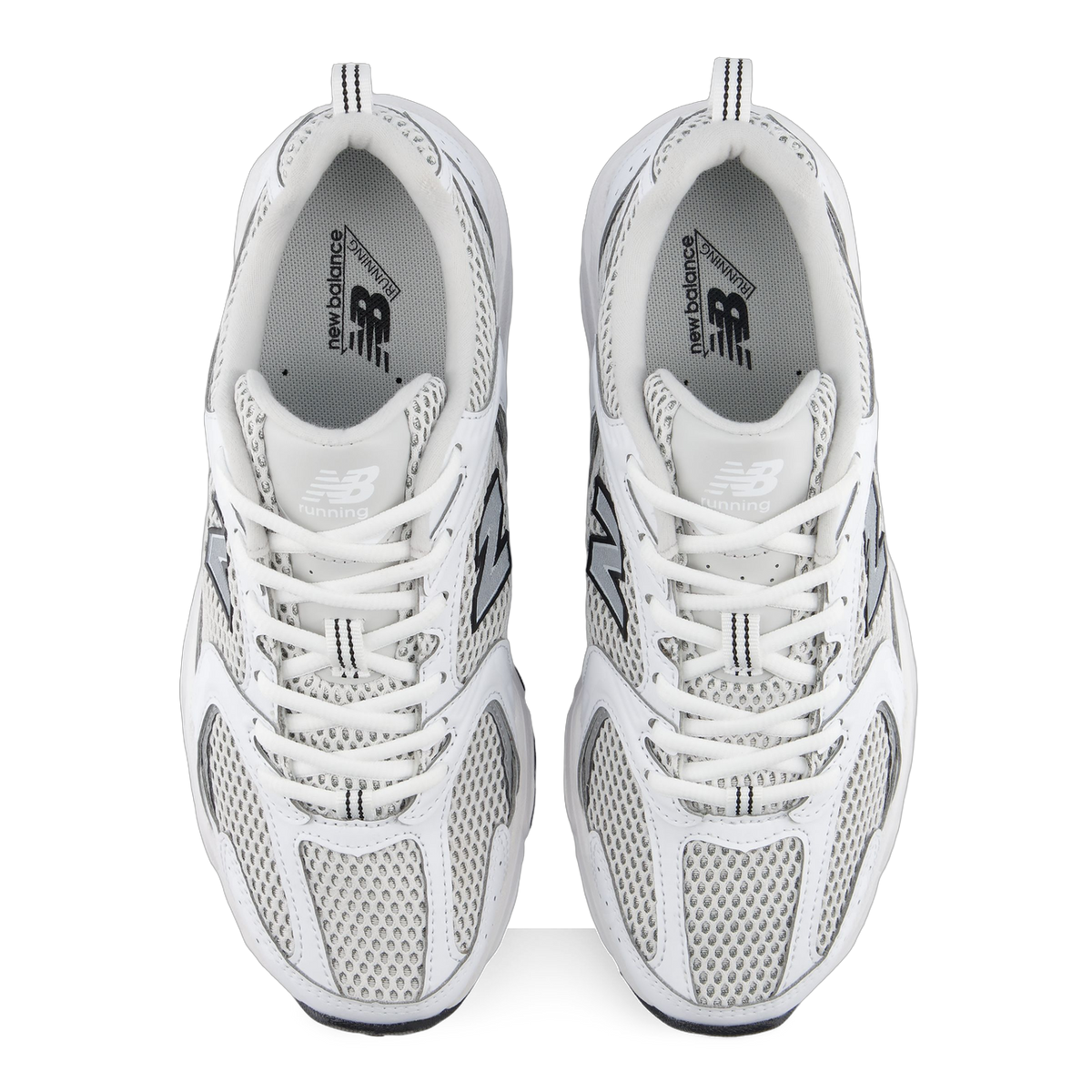Top-down view of a pair of white New Balance 530 sneakers with grey mesh panels, silver N logos, and grey New Balance Running branded insoles.