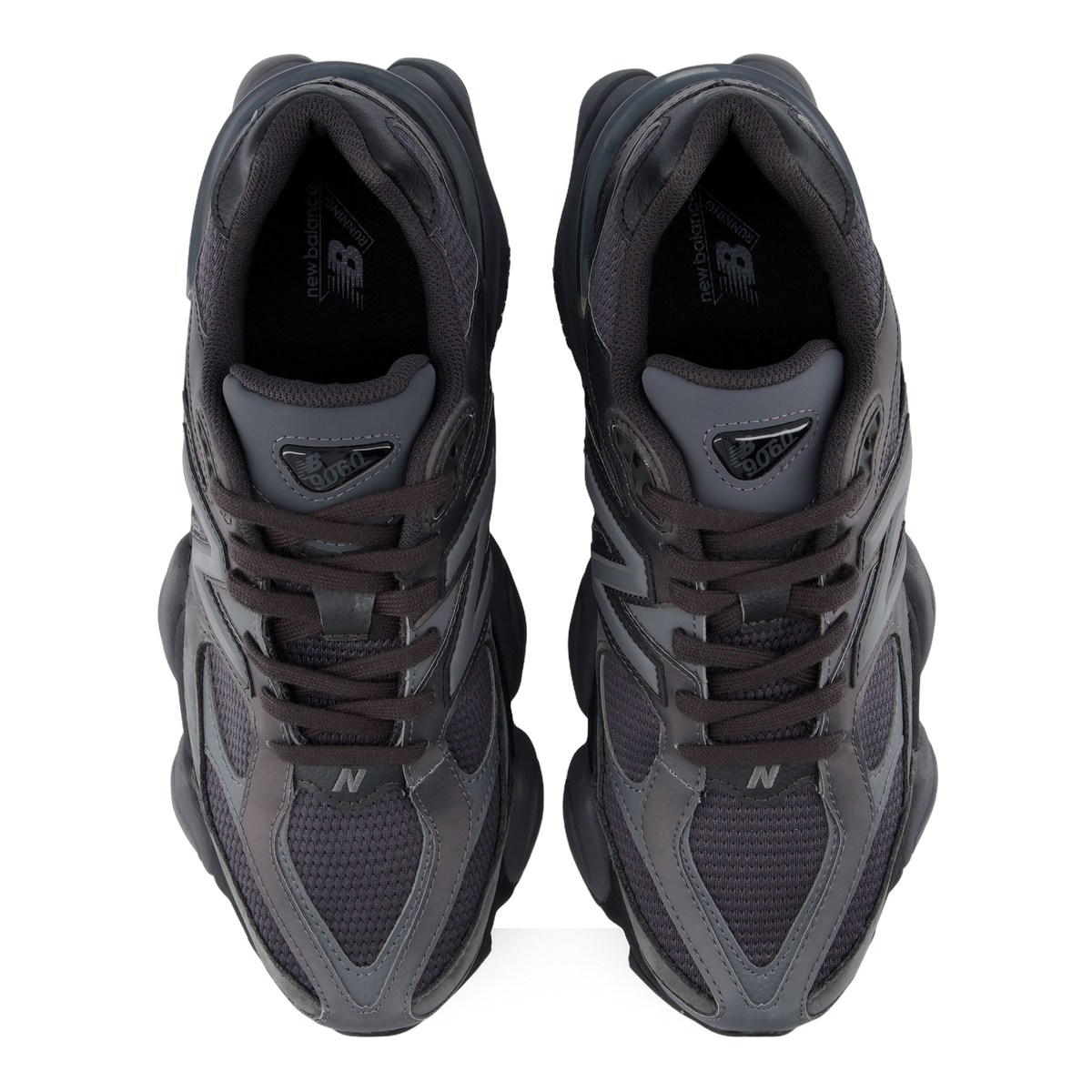 Top-down view of a pair of black and gray New Balance 9060 sneakers showing the laces, mesh tongue, and heel pull tabs with 9060 branding.