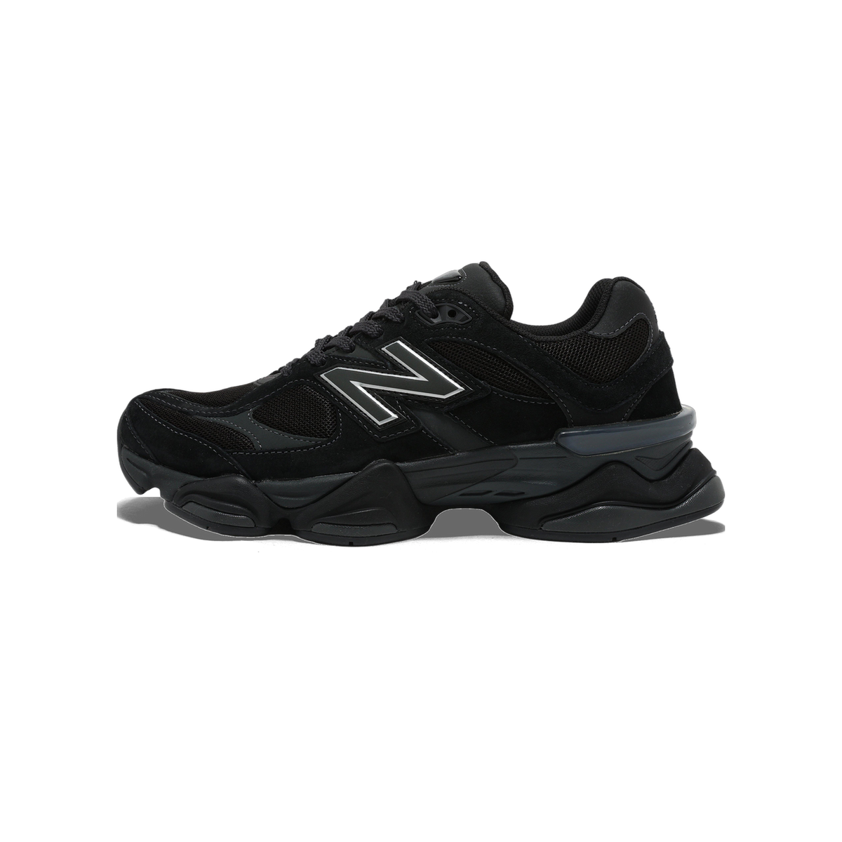 Side view of a black New Balance 9060 sneaker with suede and mesh panels, chunky midsole, and silver-outlined N logo