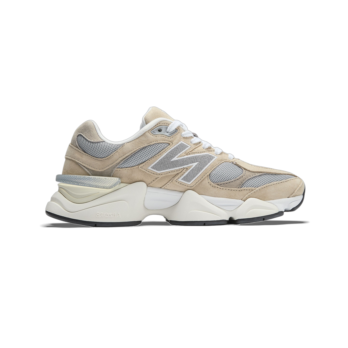 Side view of a beige New Balance 9060 sneaker with grey mesh panels, grey N logo, white laces, and a thick white midsole with black outsole, toe pointing left.