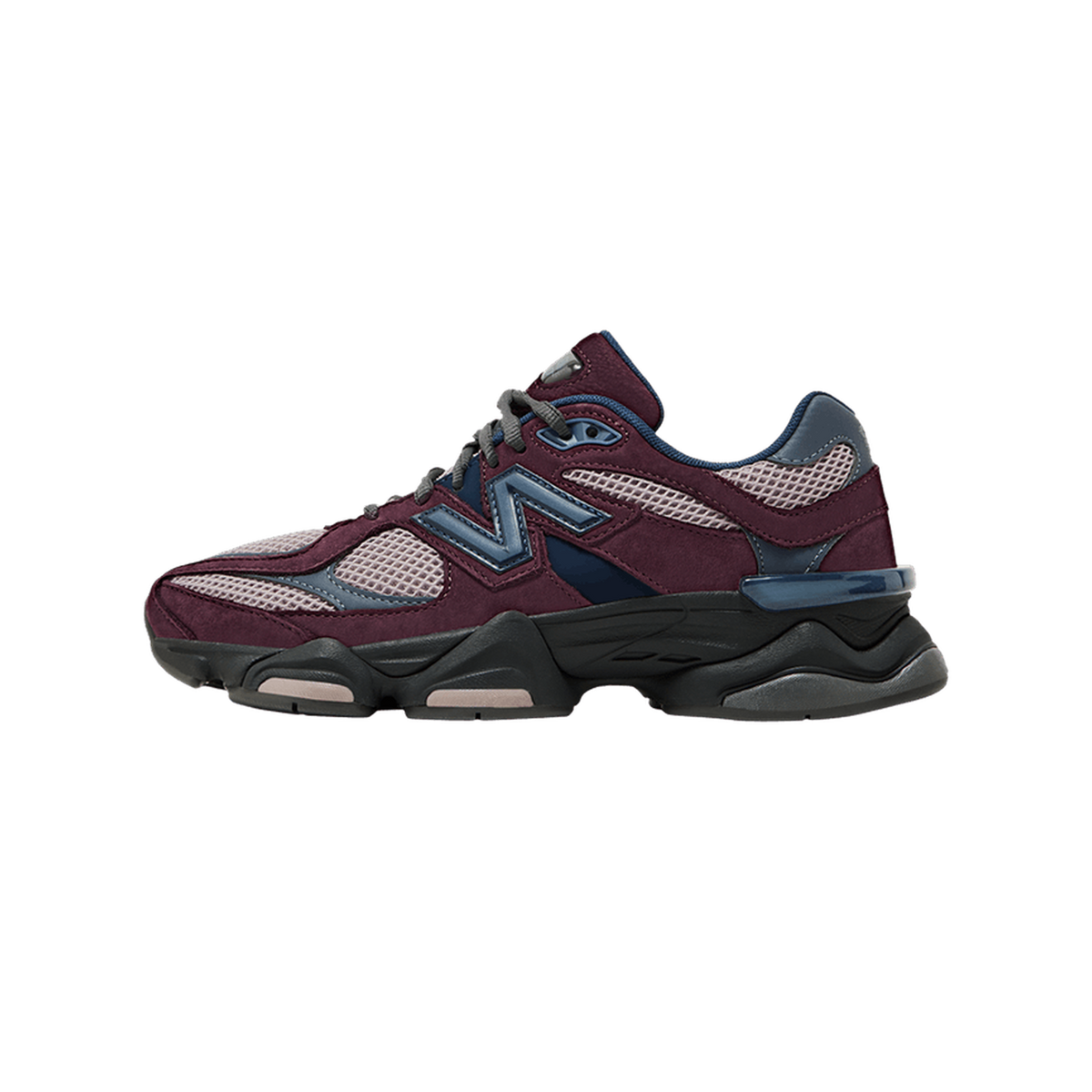 Side view of a left New Balance 9060 sneaker with toe pointing left, featuring burgundy suede overlays, pink mesh panels, navy accents, and a chunky black midsole with the N logo on the side.