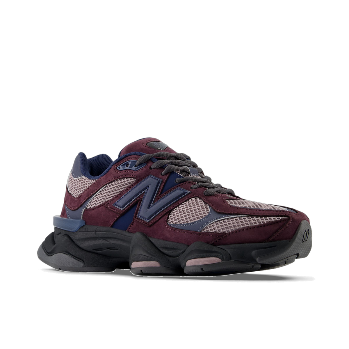 Angled side view of a New Balance 9060 sneaker in plum and brown with a navy N logo, pink mesh panels, and black chunky sole, toe pointing left.