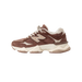 Side view of a brown New Balance 9060 sneaker with tan N logo, cream laces, and a chunky off-white midsole with gum accents.