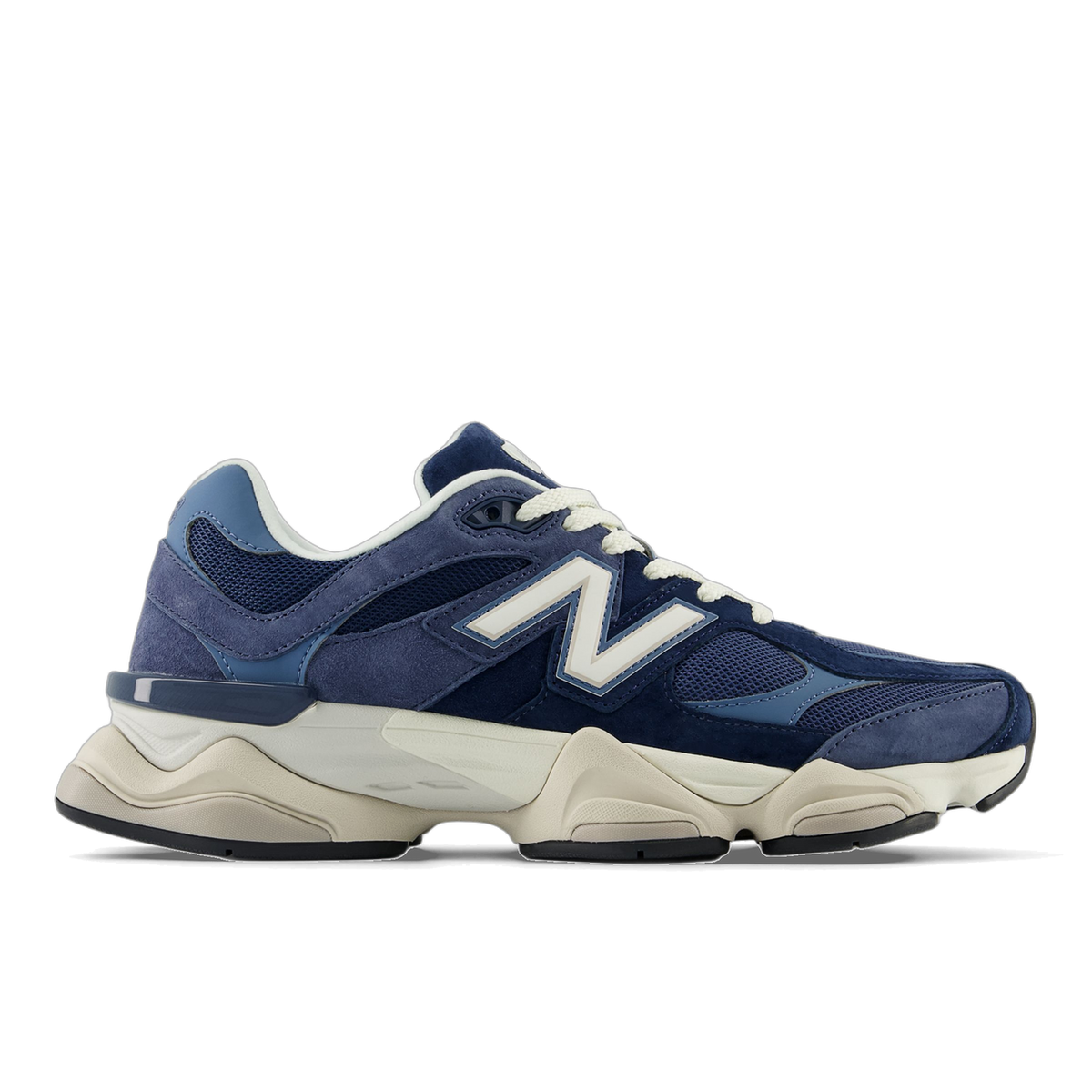 Side view of a navy and blue New Balance 9060 sneaker with white N logo, cream laces, and a chunky off-white midsole with black outsole, toe pointing left.