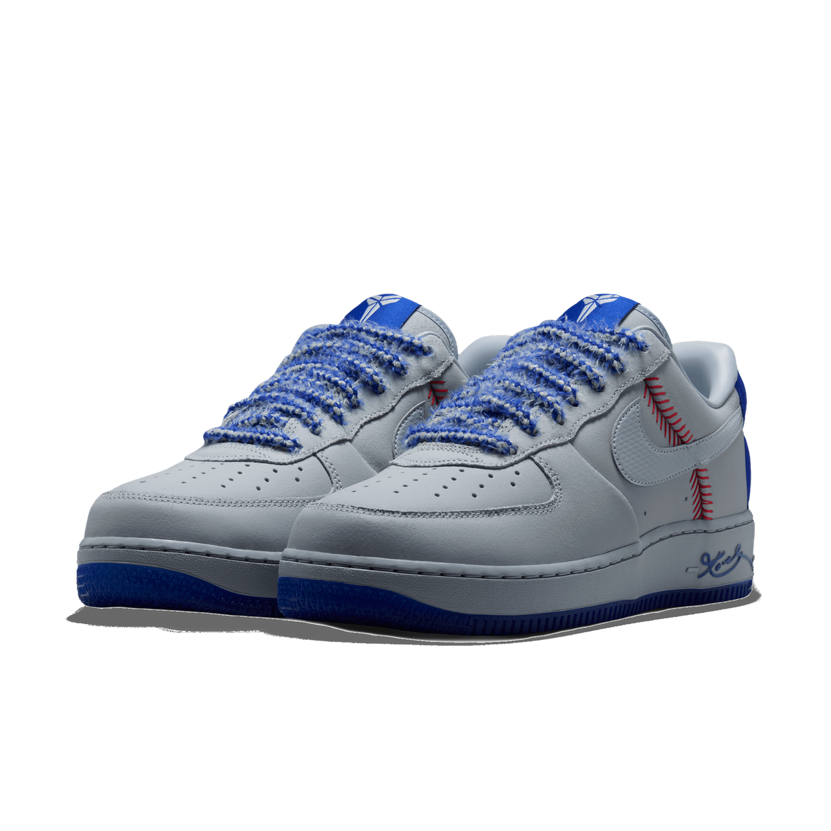 Pair of white and grey Nike Air Force 1 Low sneakers with blue woven laces, red baseball-stitch detailing, and blue outsoles, angled toward the front left.