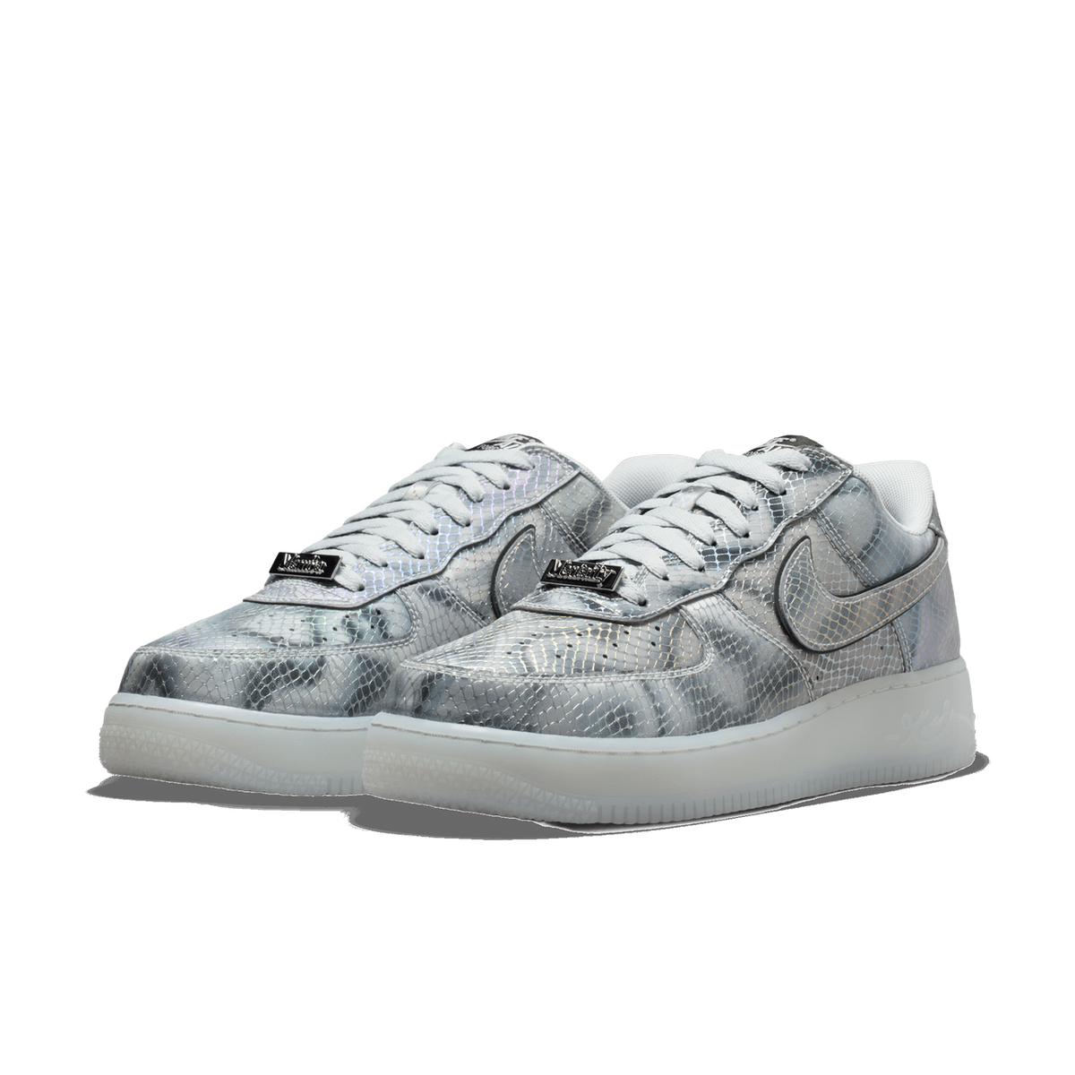 A pair of silver, iridescent snakeskin-patterned low-top sneakers displayed side by side at an angle, showing the laces, metallic tongue tags, and translucent frosted outsoles.