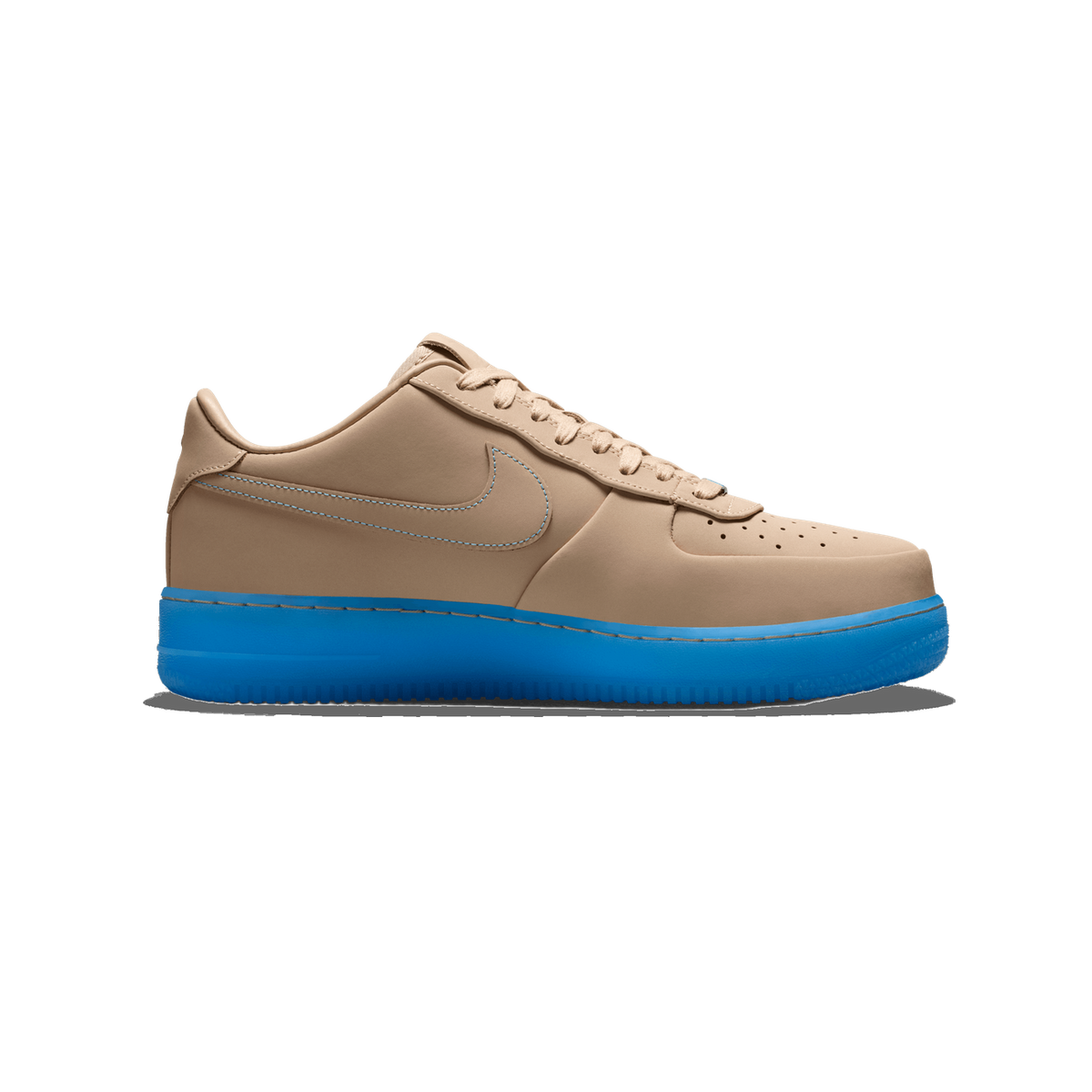 Side profile of a single beige shoe with the toe pointing left, showing a tan upper with a Nike swoosh outlined in blue stitching, perforations on the toe box, and a bright blue translucent sole.