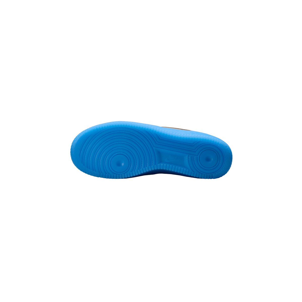 Underside of a sneaker showing a bright blue rubber outsole with concentric circular tread patterns, a visible Nike swoosh logo near the arch, and a sliver of tan-brown upper visible at the top edge.