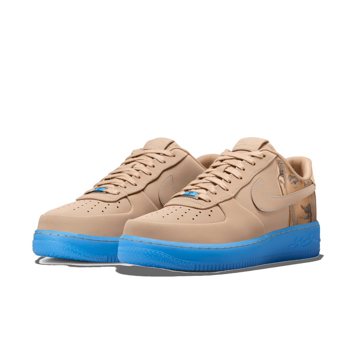 A pair of beige Nike Air Force 1 Low sneakers shown side by side, angled toward the left, with a sand-toned upper, a bright blue translucent midsole, and a printed photographic image on the heel panel of the right shoe.