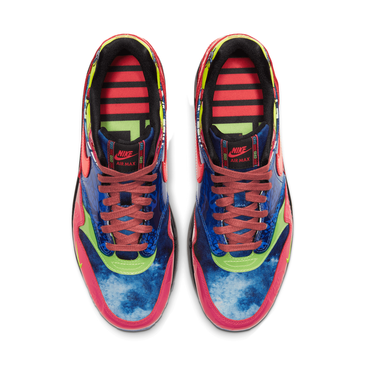 Top-down view of a pair of Nike Air Max 1 sneakers with blue tie-dye patterned uppers, green swoosh logos, crimson accents, and maroon laces.