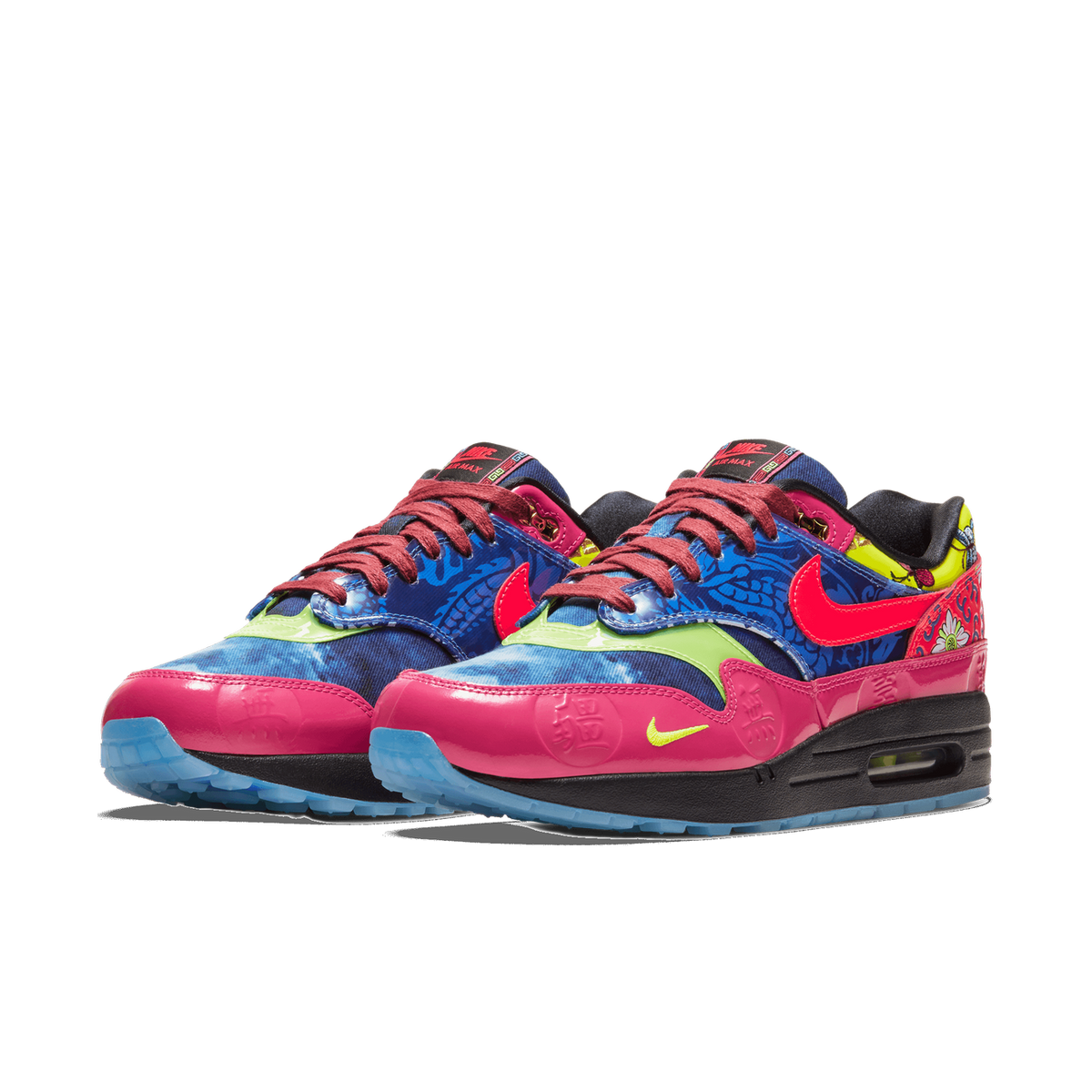 Front-angled view of a pair of Nike Air Max 1 sneakers with pink toe caps, blue floral-patterned uppers, neon green accents, crimson lace swooshes, and burgundy laces.