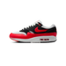 Side view of a Nike Air Max 1 sneaker with a red toe box and heel, black suede overlays, grey mesh panels, and a red swoosh logo, toe pointing left.